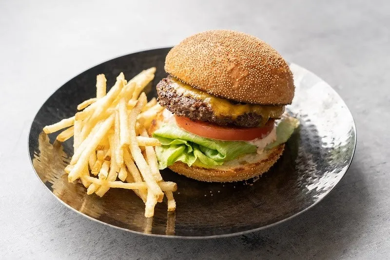 ハンバーガーとフライドポテトが銀色の皿に乗せられた写真です。