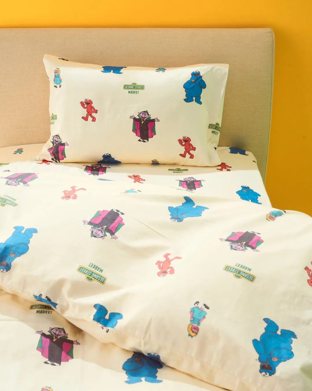 セサミストリートのキャラクターが描かれた寝具セットの写真です。枕カバーとシーツには、エルモ、クッキーモンスター、伯爵、そしてセサミストリートのロゴがプリントされています。