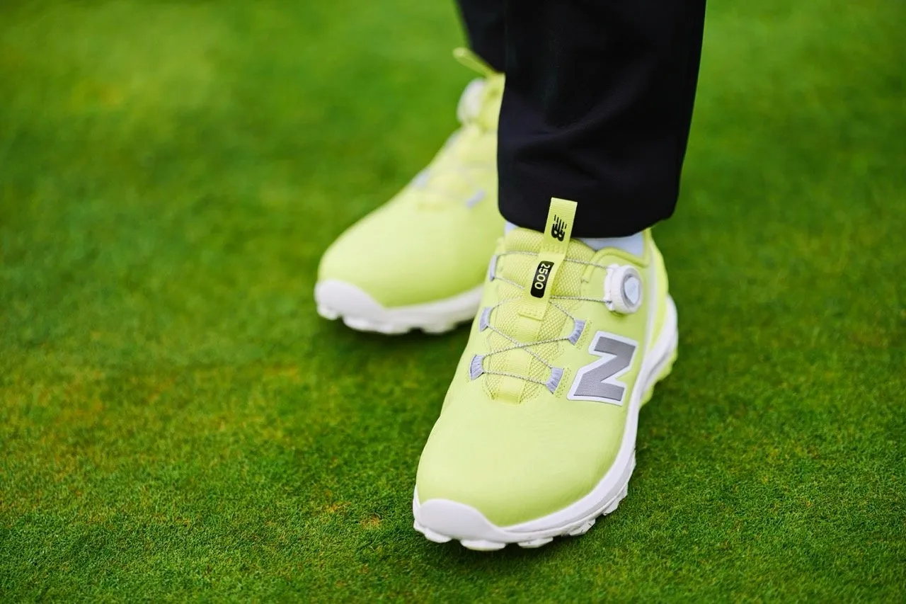 鮮やかな黄緑色のゴルフシューズが芝生の上に置かれている様子。