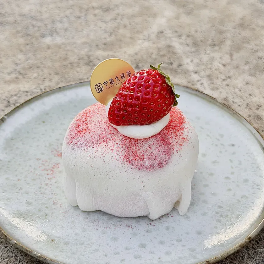 お皿に載った、イチゴがトッピングされた白いデザート