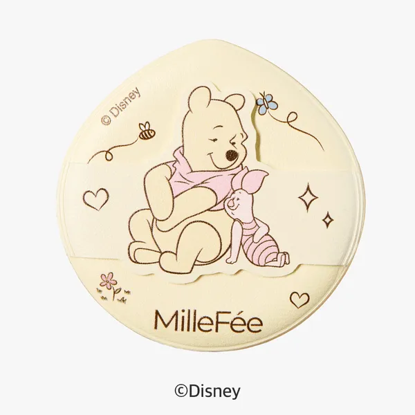 くまのプーさんとピグレットが描かれた、丸いケースの画像です。背景は薄い黄色で、プーさんとピグレットはケースに描かれています。プーさんはピンク色のスカーフをしており、ピグレットはピンク色の服を着ています。ケースには「MilleFée」の文字と、ディズニーのロゴがあります。
