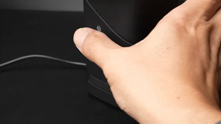 黒い物体に触れている人間の手のクローズアップ。