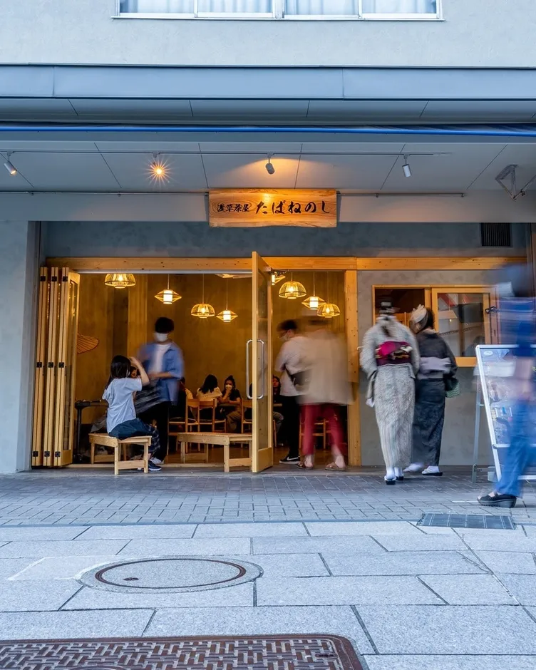 店の入り口で着物姿の女性2名と、店内で食事をする人々の様子が写っている写真